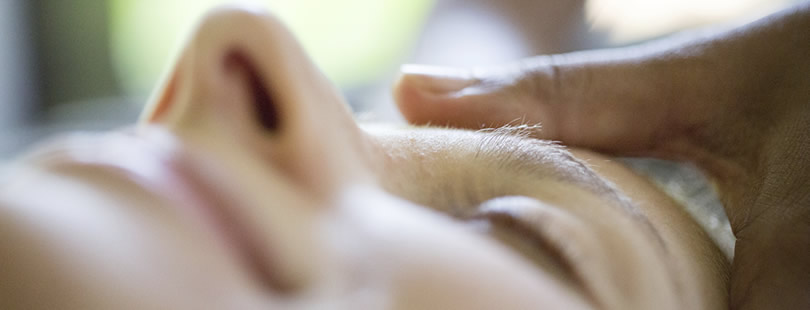 A close up image of a woman that is getting her forehead massaged