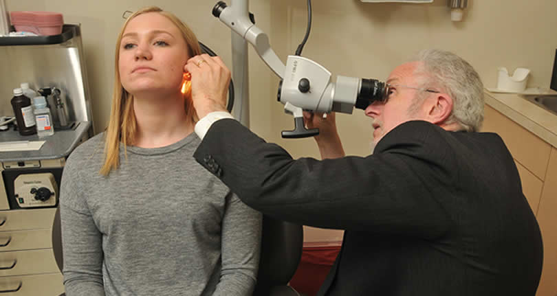 Doctor performing ear exam on female patient